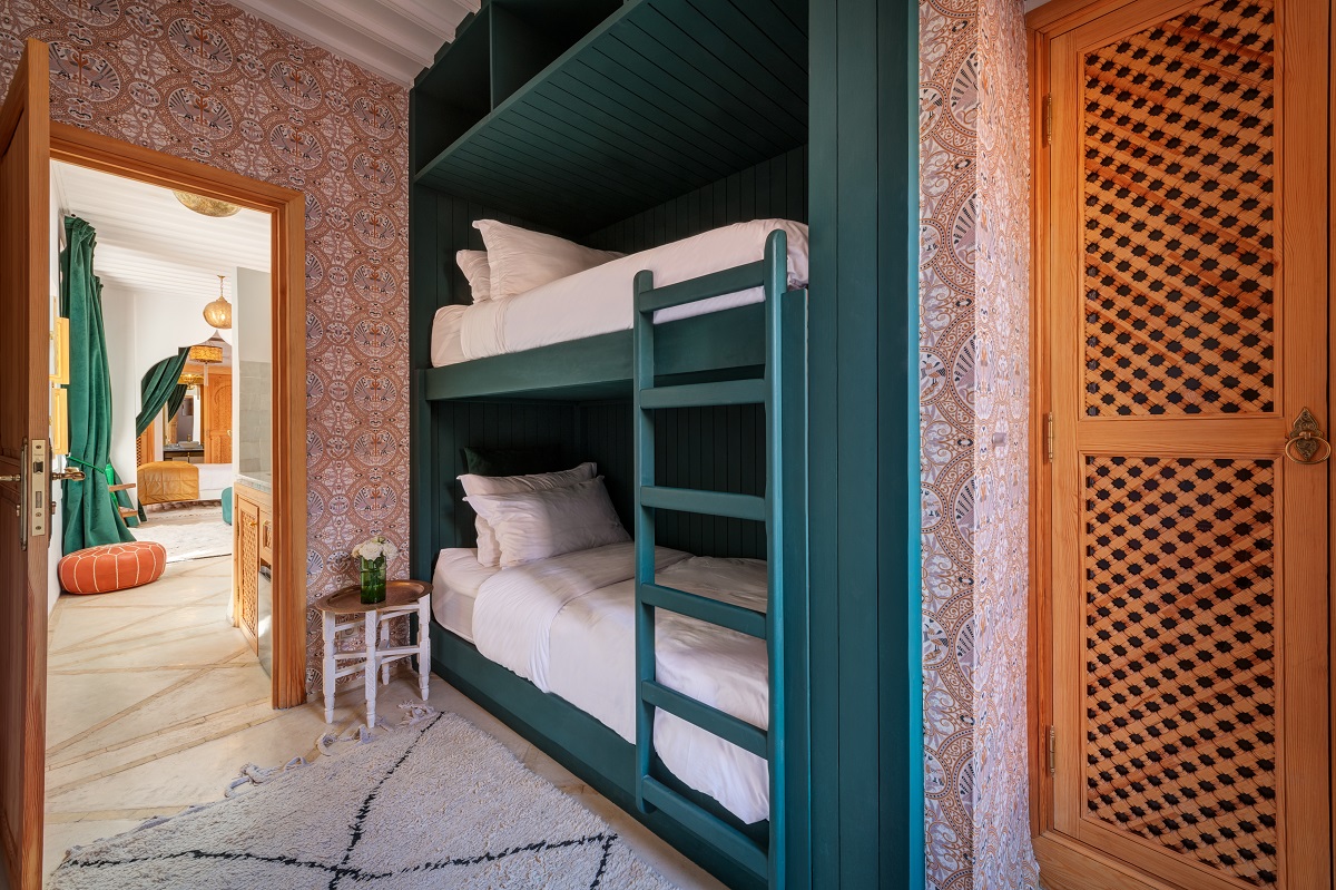 dark green bunk beds with patterned wallpaper and moroccan carpet