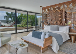 guestroom with wooden headboard divider detail and view to terrace with hammock at St Regis Kanai Resort by Chapi Chapo